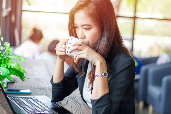 Mulher de negócios asiática está trabalhando e bebendo café no café na hora de relaxar — Fotografia de Stock