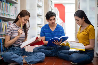 Grup Asyalı Öğrenciler Gülümseyin, kitap okuyun ve defter kullanın 