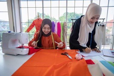 Müslüman kadın moda tasarımcısının çalıştığı, akıllı telefon ve tablet kullandığı küçük bir işletme.
