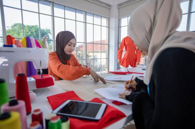 Müslüman kadın moda tasarımcısının çalıştığı, akıllı telefon ve tablet kullandığı küçük bir işletme.