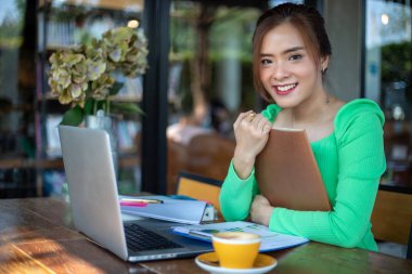 Kitap okuma ve gülümseyen Asyalı kadınlar ve başarılı bir ofiste çalıştıktan sonra bir kafede mutlu Relaxing.