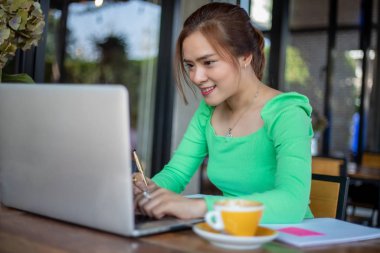 Asyalı iş kadınları gülümsüyor ve notları analiz belgeleri ve grafik finansal diyagramı için kullanıyor ve kahve dükkanında kahve içiyor.
