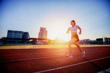 Stadyumda koşan Asyalı genç fitness kadın koşucusu 