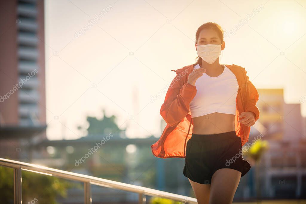 Asian Young fitness sport woman running  and she wears a  mask for protective Dust and pollution on city 
