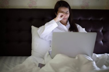 Asyalı kadın geceleri çalışmak için defter kullanıyor. Esniyor ve uykulu..