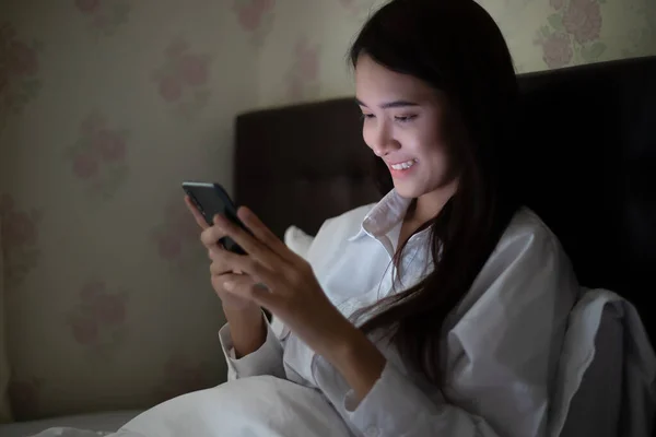 Asyalı Kadın Gece Yatakta Cep Telefonu Kullanıyor Gülümsüyor Evde Eğleniyor — Stok fotoğraf