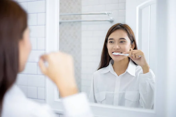 Asian women squeezing toothpaste and brushing their teeth in the bathroom in the morning.