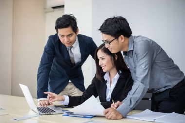 Asyalı işadamları ve grup iş ortakları için not defteri kullanıyor toplantıda belgeler ve fikirler tartışıyorlar ve iş kadınları mutlu bir şekilde gülümsüyorlar. 