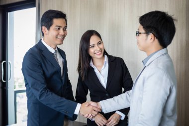 El sıkışan ve sözleşme ve bir buluşma bitirme imzalamak için onların anlaşma gülümseyen Asya iş adamları