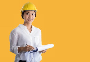 Asyalı kadın mühendisler denetliyor, çalışıyor ve ofiste planları tutuyor.