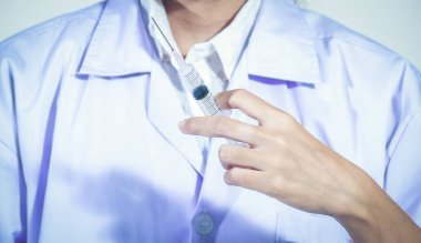 Doktor elinde şırınga ve tıbbi plastik aşı ekipmanlarıyla iğne tutuyor. Hemşire ya da doktor. Tedavi için sıvı ilaç veya narkotik koronavirüs% 2Fcovid-19, hastanede sağlık hizmetleri.