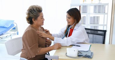 Doktor hastanedeki yaşlı kadının ciğerlerini kontrol etmek için stetoskop kullandı..