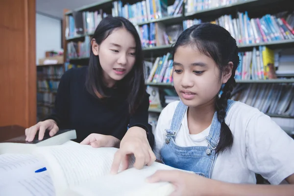 Δύο Ασιάτισσες Μαθήτριες Διαβάζουν Βιβλία Και Χρησιμοποιούν Σημειωματάριο Στη Βιβλιοθήκη — Φωτογραφία Αρχείου