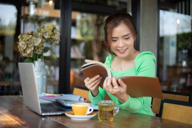 Kitap okuma ve gülümseyen Asyalı kadınlar ve başarılı bir ofiste çalıştıktan sonra bir kafede mutlu Relaxing.