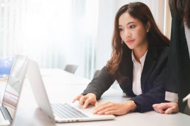 İş kadınları ve Mühendis Grubu, iş ortakları için defter kullanıyor. Toplantıda belge ve fikirleri tartışıyorlar. Ve iş kadınları mutlu bir şekilde gülümsüyor. 