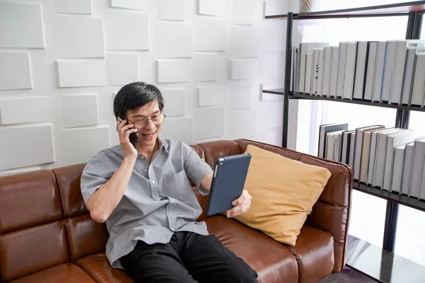 Älterer Asiatischer Mann Spielt Tablet Und Videotelefonie Auf Dem Sofa — Stockfoto