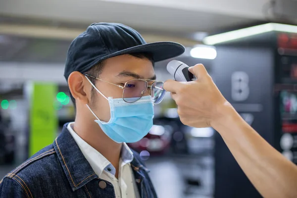 아시아 사람들은 독감의 온도를 측정하고 코로나 바이러스를 얼굴에 보호용 마스크를 — 스톡 사진
