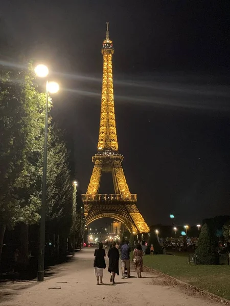 PARIGI, FRANCIA - 24 luglio 2019: La Torre Eiffel di notte. La gente cammina vicino a La Tour Eiffel la sera. Luce da un lampione. Paesaggio urbano notturno. Simbolo della Francia al buio. Colpo verticale — Foto Stock