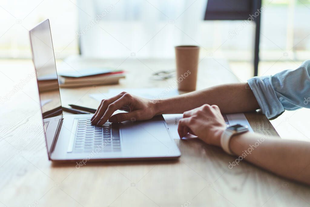 Side view of woman typing on laptop keyboard, closeup