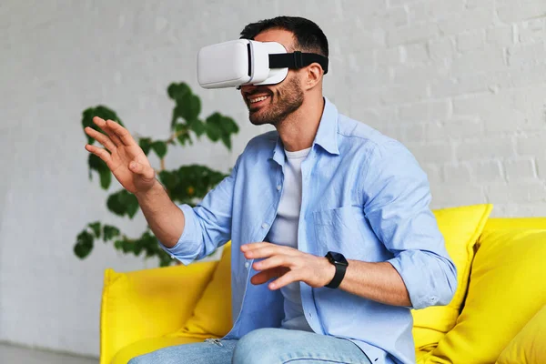 Excited man in virtual reality glasses smiling while having VR experience