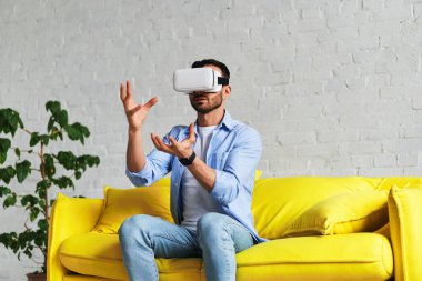 Front view of man using virtual reality glasses, touching and holding something with hands