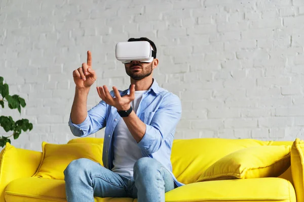 Tampilan depan manusia menggunakan kacamata virtual reality, menampilkan satu tangan ke atas dan memegang sesuatu di tangan yang lain — Stok Foto