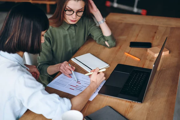 Side view of two businesswoman analyse, make notes on graphics and charts — Stockfoto