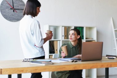 Two serious businesswomen having a meeting using laptop in office