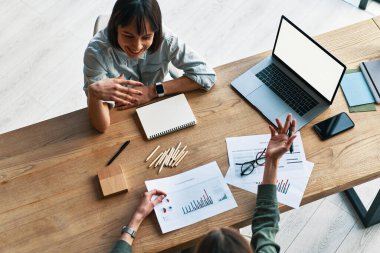 Top view of two happy dreamy businesswomen having a meeting in office