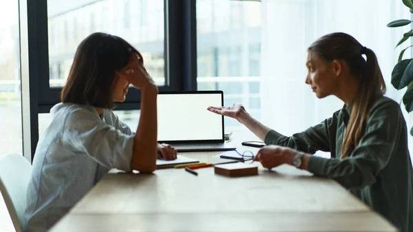 Two happy dreamy businesswomen having a meeting using laptop in office