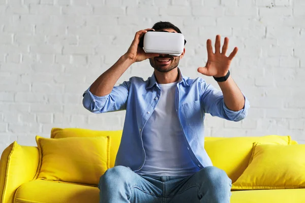 Excited man in virtual reality glasses smiling catching while having VR experience — Stockfoto