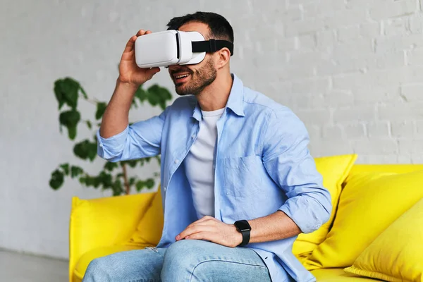 Excited man in virtual reality glasses smiling while having VR experience — Stockfoto