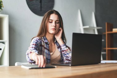 Güzel bir kadın dizüstü bilgisayarla çalışıyor, notlar alıyor ve düşünüyor.