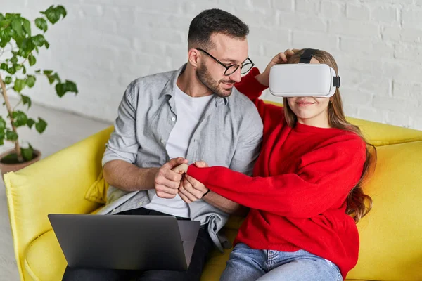 Jong schattig paar in VR bril spelen video game met joystick, zittend op de bank — Stockfoto