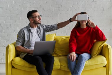 VR gözlüklü genç çift sarı koltukta ilk sanal gerçeklik deneyimini yaşıyor.