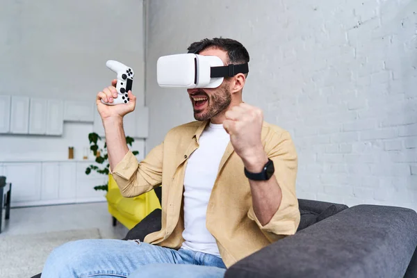Jonge emotionele man in VR bril spelen video game met joystick, tevredenheid, geluk, opwinding, vreugde van de overwinning, winnen — Stockfoto