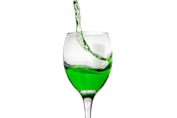 Wineglass with splashing drops of green alcohol cocktail — Stock Photo, Image