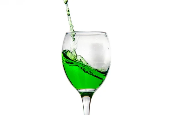 Wineglass with splashing drops of green alcohol cocktail — Stock Photo, Image