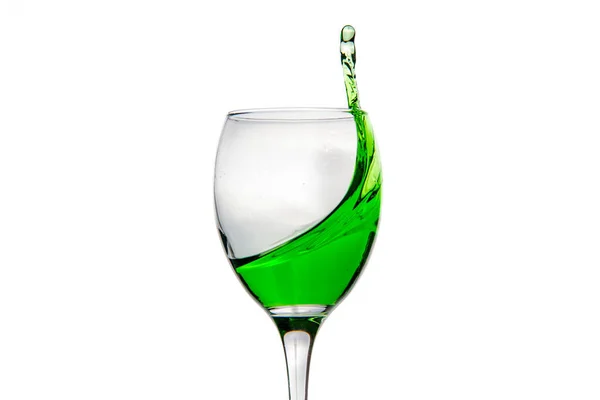 Wijnglas met spatten druppels groene alcohol cocktail — Stockfoto