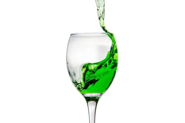 Wineglass with splashing drops of green alcohol cocktail — Stock Photo, Image