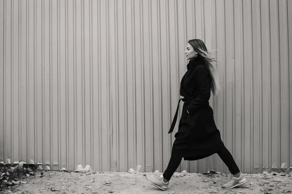 Mooie jonge vrouw in casual kleding lopen tegen het hek — Stockfoto