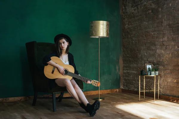 Jeune femme de mode jouant à la guitare dans une chambre verte élégante — Photo