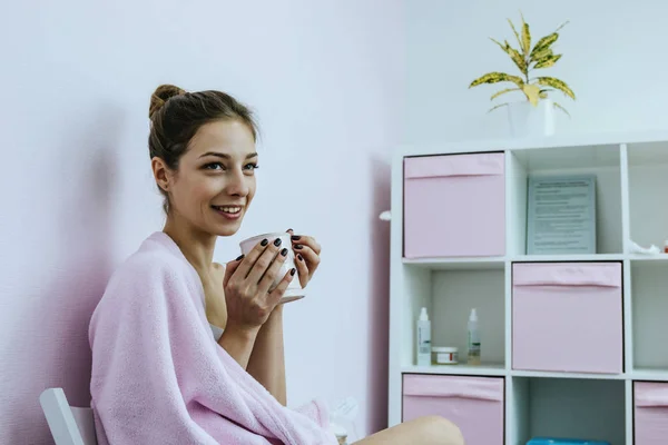 Jovem com xícara e xadrez rosa no salão de beleza — Fotografia de Stock