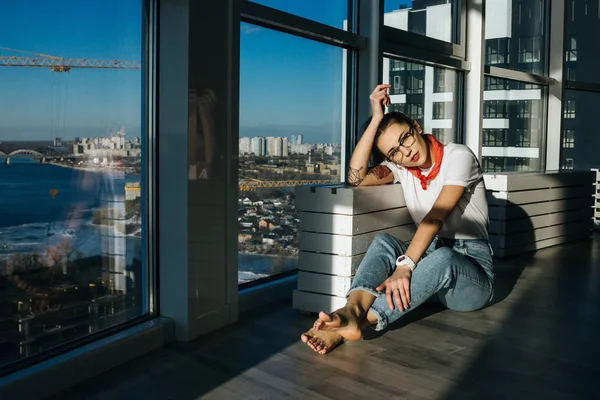 Junge Mode-Frau aus den 90er Jahren sitzt am riesigen Fenster — kostenloses Stockfoto