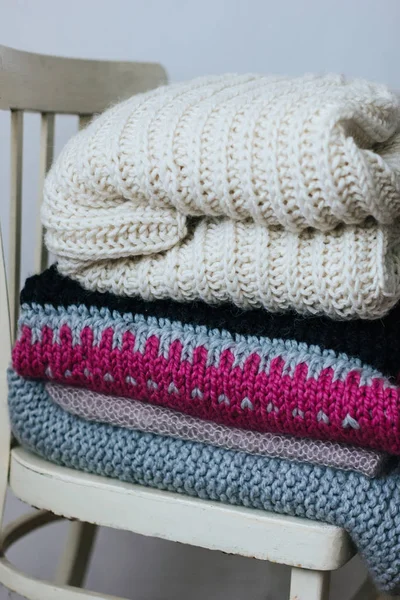 Уютная куча теплых свитеров на стуле — стоковое фото
