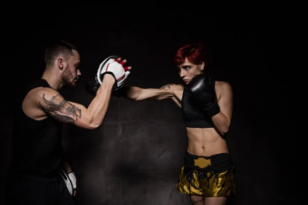 Mujer boxeadora golpeando guantes de entrenamiento sostuvo un entrenador de boxeo — Foto de Stock