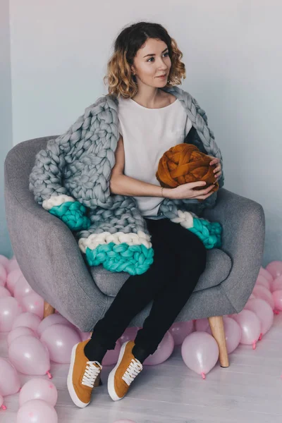 Fiatal nő ül a széken, narancs merinó gyapjú labda — Stock Fotó