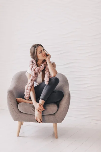 Beautiful young woman sitting in arm-chair — Stock Photo, Image