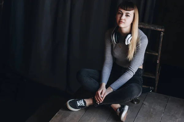 헤드폰으로 스케이트 보드에 앉아 어린 소녀 — 스톡 사진