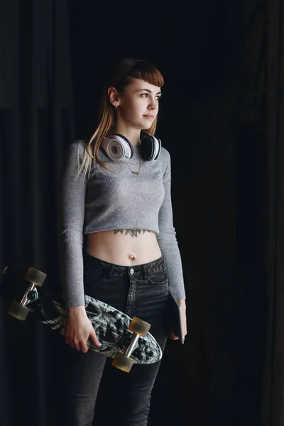 Jeune fille avec skateboard et écouteurs — Photo